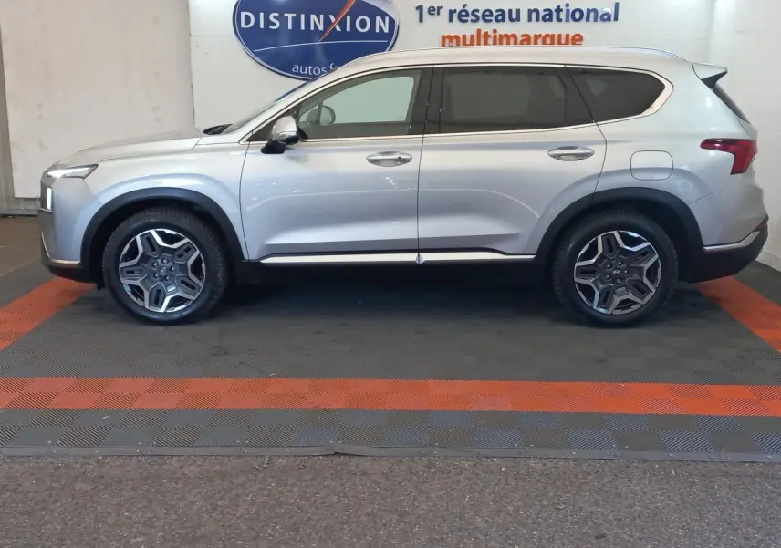 Vue latérale droite d'un Hyundai Santa Fe gris clair 2021 hybride rechargeable, avec jantes alliage et vitres teintées.