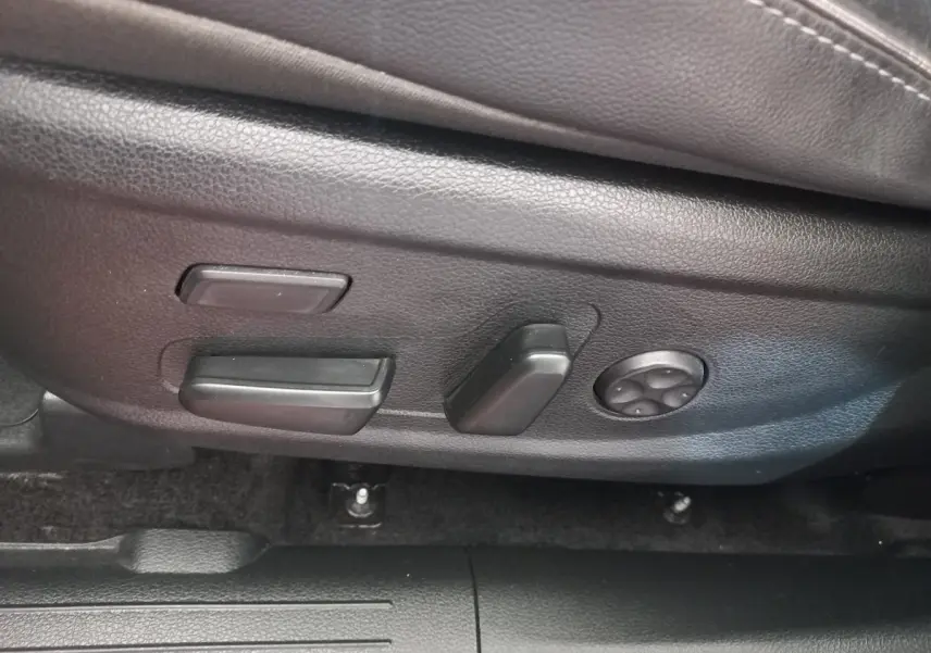 Gros plan sur les commandes de réglage électrique du siège conducteur noir dans un Hyundai Santa Fe gris clair 2021.
