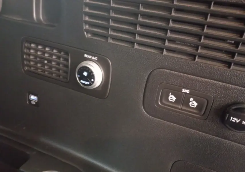 Détail du panneau de commande arrière noir du Hyundai Santa Fe hybride, avec réglage climatisation et boutons sièges 2e rangée.