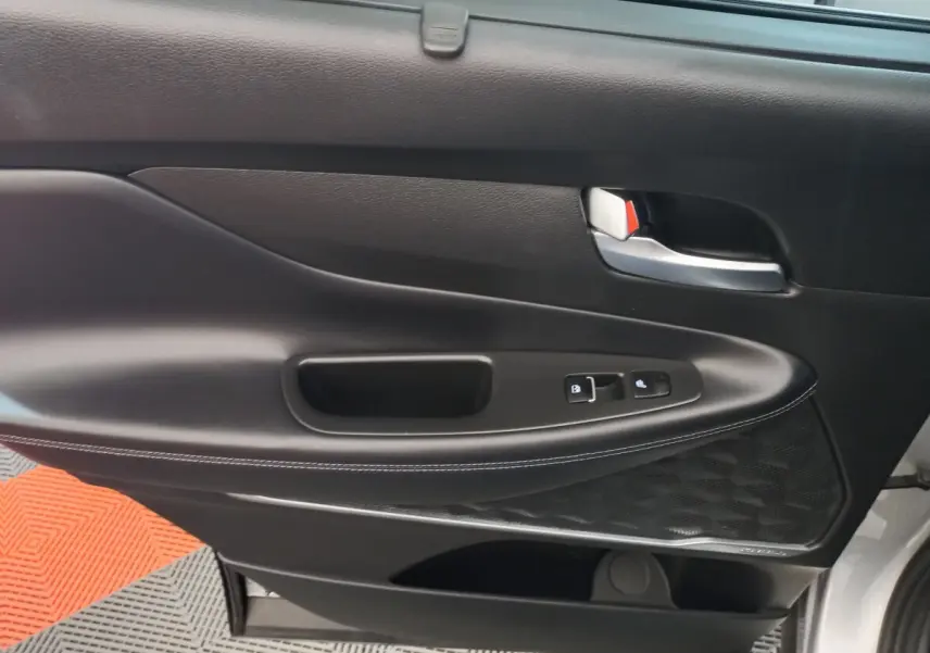 Gros plan sur la porte intérieure côté gauche noire avec commandes de verrouillage et haut-parleur Harman Kardon.