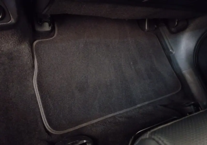 Tapis de sol noir côté passager avant du Hyundai Santa Fe hybride rechargeable gris clair, vue intérieure rapprochée.