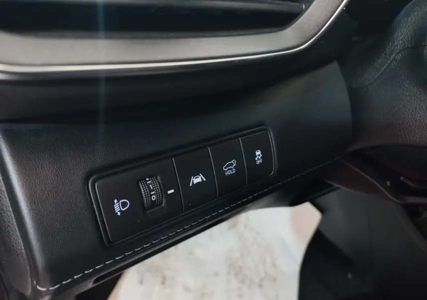 Gros plan sur les commandes noires du tableau de bord côté gauche du Hyundai Santa Fe gris clair hybride rechargeable.