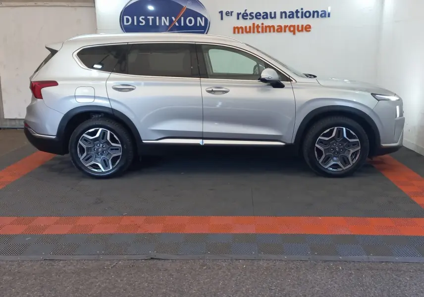 Vue de profil côté gauche du Hyundai Santa Fe gris clair hybride rechargeable, avec jantes alliage et toit ouvrant électrique visible.