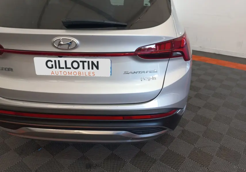 Vue arrière du Hyundai Santa Fe gris clair avec feux LED et logo plug-in visible sur un sol à motifs.