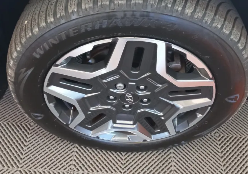Gros plan sur la jante alliage grise et noire avec logo Hyundai, montée sur pneu hiver Winterhawk 4.