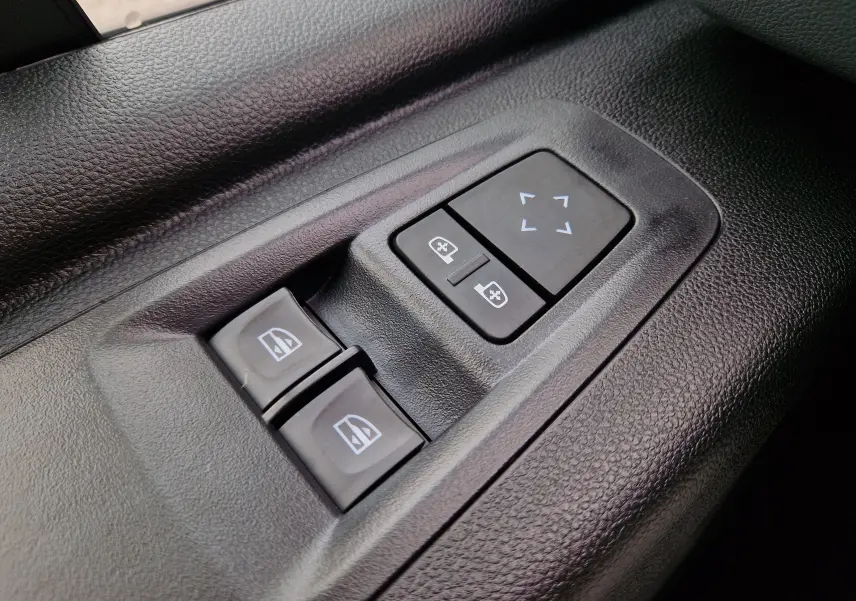 Gros plan sur les commandes de réglage des rétroviseurs et des vitres électriques côté conducteur du Renault Master gris urbain 2026.