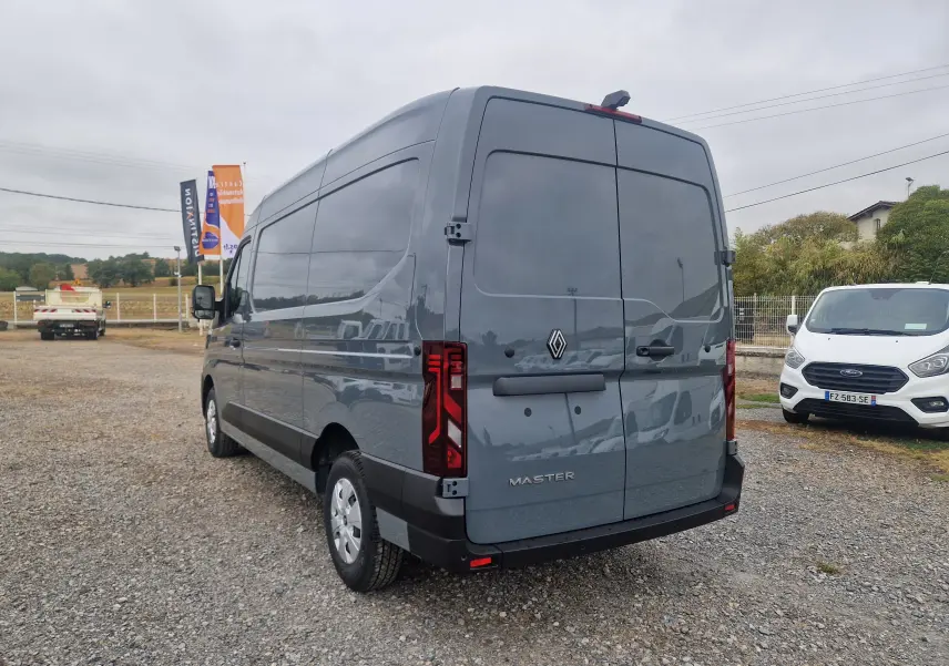 Vue 3/4 arrière droite d’un Renault Master gris urbain 2026 avec portes arrière fermées et feux rouges distinctifs.