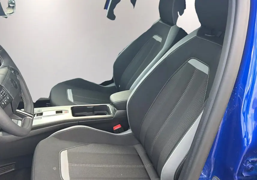 Vue intérieure côté conducteur de l’Opel Mokka Electric 156 gs bleu, sièges noirs avec surpiqûres grises et accoudoir central.
