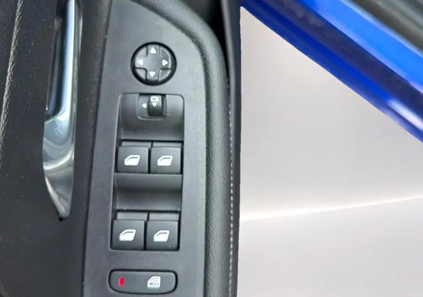 Gros plan sur les commandes des vitres et rétroviseurs côté conducteur d’un Opel Mokka Electric bleu 2025.