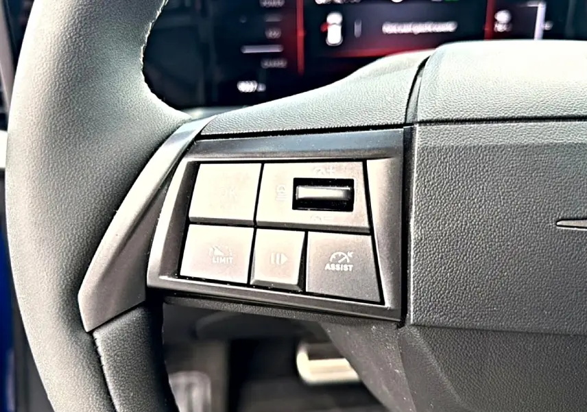 Gros plan sur les commandes gauche du volant noir de l'Opel Mokka Electric 156 gs, avec boutons multifonctions visibles.