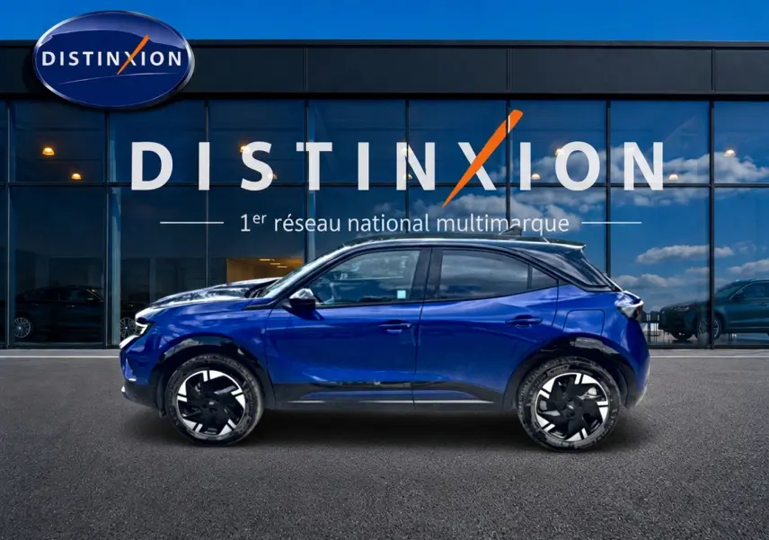 Vue de profil côté gauche d'un Opel Mokka Electric 156 GS bleu devant une vitrine Distinxion.