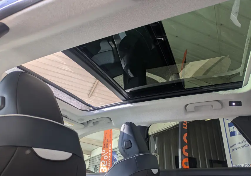 Vue intérieure du toit panoramique ouvert du Citroën C5 Aircross gris platinium avec sièges avant en cuir noir.