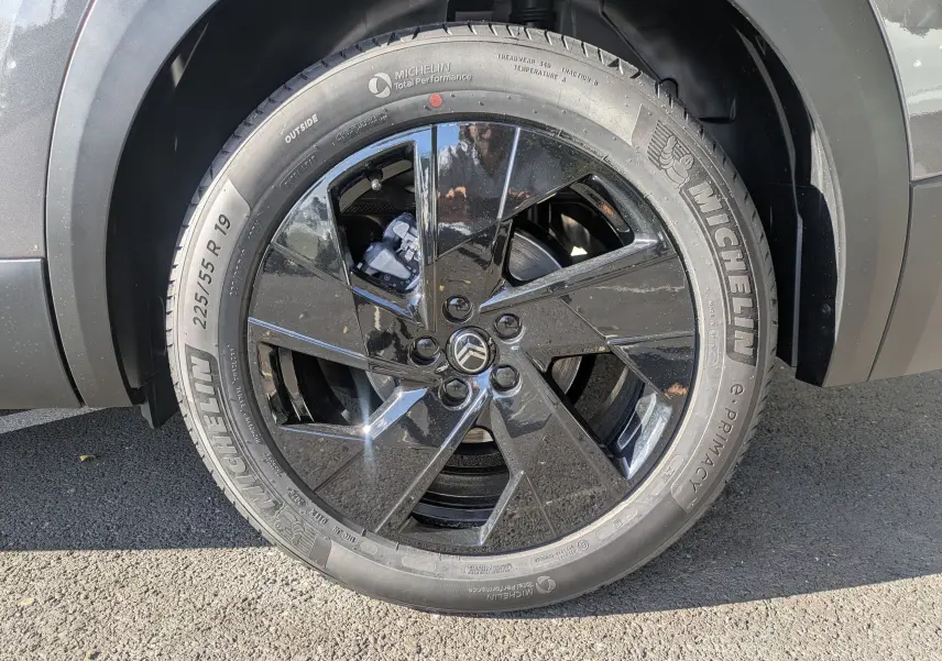 Gros plan sur la roue avant gauche du Citroën C5 Aircross hybride gris platinium avec jante noire brillante.