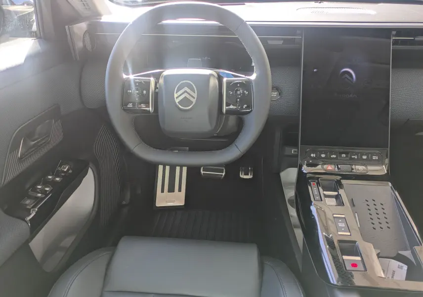Vue intérieure avant centrée sur le volant noir et la console centrale brillante du Citroën C5 Aircross hybride 2026.