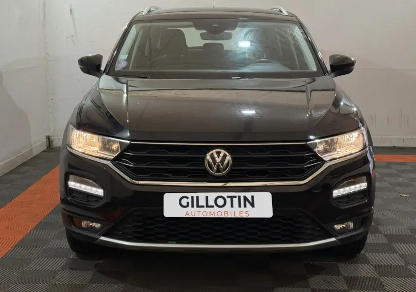 Vue frontale d'un Volkswagen T-Roc noir 2020 avec phares allumés et calandre hexagonale distinctive.