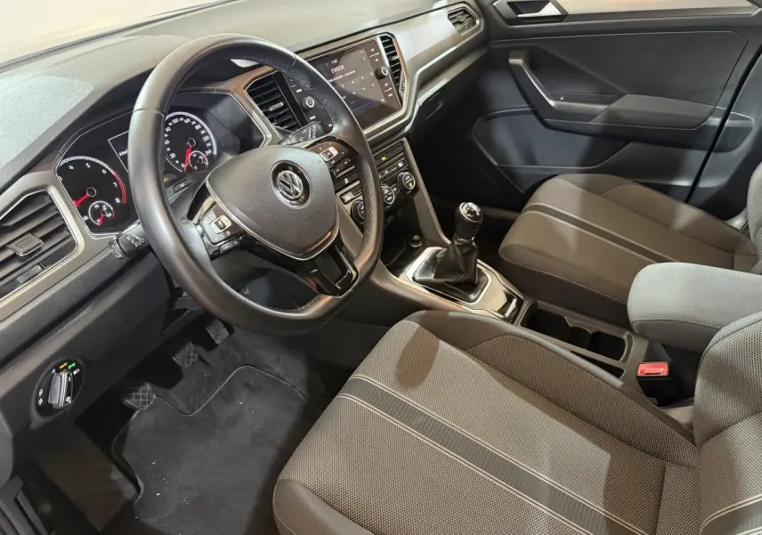 Intérieur noir du Volkswagen T-Roc 1.0 TSI 115 Lounge Business, vue côté conducteur sur volant cuir et console centrale.