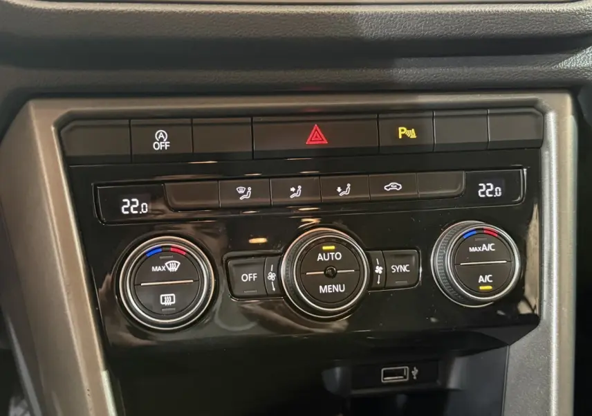 Panneau de commande de climatisation noir du Volkswagen T-Roc 2020, avec affichage digital et boutons circulaires.