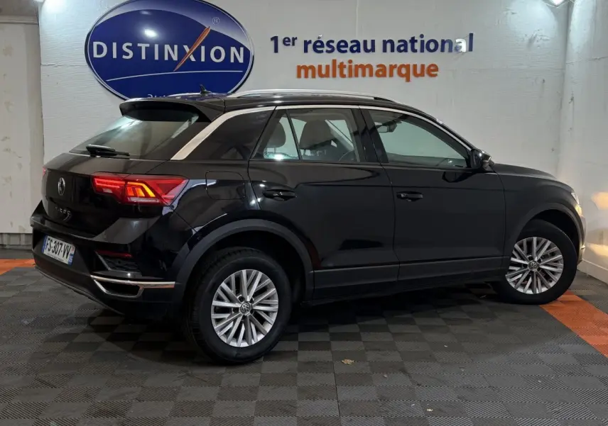 Vue 3/4 arrière côté droit d'un Volkswagen T-Roc noir 2020 dans un showroom avec logo Distinxion en arrière-plan