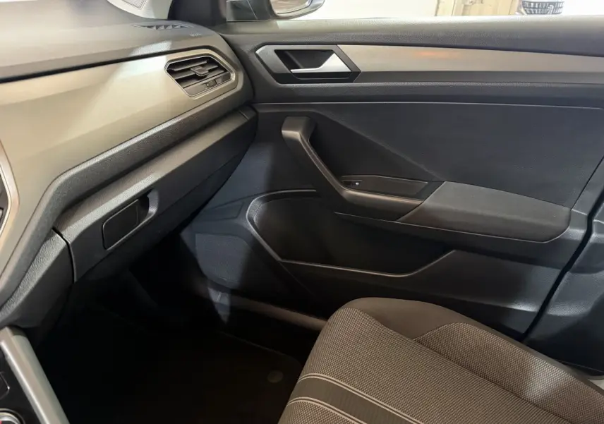 Vue intérieure côté passager du Volkswagen T-Roc 1.0 TSI 115 Lounge Business 2020 avec sellerie grise et tableau de bord noir.