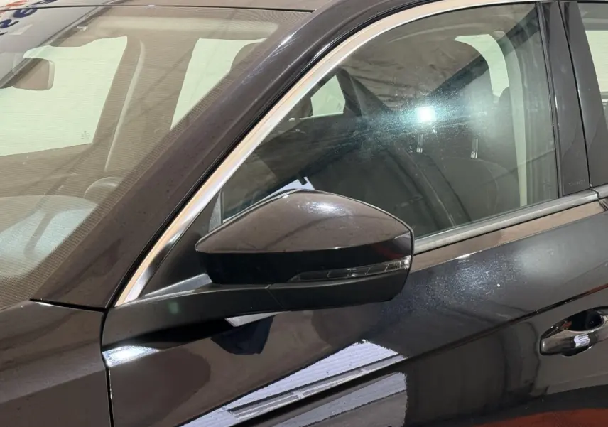 Gros plan sur le rétroviseur côté gauche d'un Volkswagen T-Roc noir 2020 avec portière et vitre avant visibles.