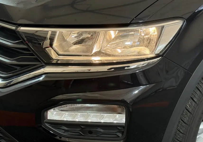 Gros plan sur le phare avant droit et antibrouillard d’un Volkswagen T-Roc noir, finition Lounge Business 2020.