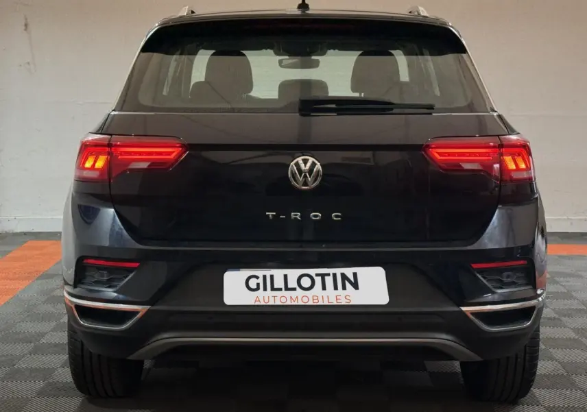 Vue arrière d'un Volkswagen T-Roc noir 2020 avec feux LED allumés et logo centré sur un sol damier.