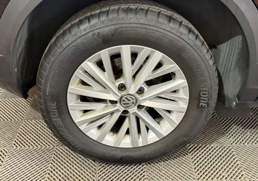 Gros plan sur la roue avant gauche du Volkswagen T-Roc noir, mettant en valeur la jante argentée et le pneu Bridgestone.