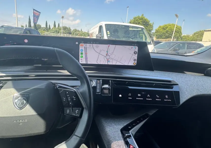 Vue intérieure du tableau de bord du Peugeot 3008 Hybrid 2025, avec volant compact, écran tactile et navigation affichée.