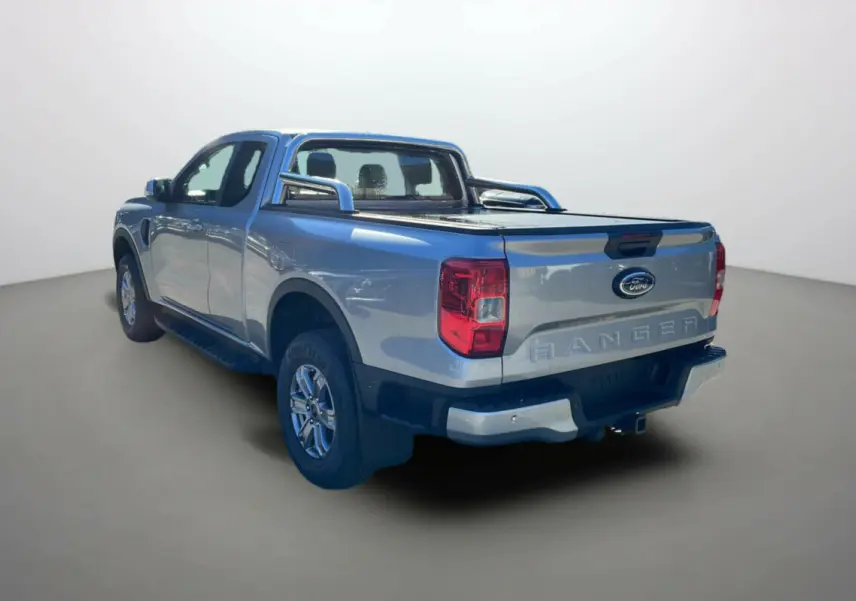 Vue 3/4 arrière droite du Ford Ranger gris iconic avec arceaux inox et bac de benne couvert par rideau coulissant.