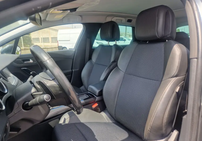 Vue intérieure côté conducteur de la Peugeot 508 SW 2015, sièges en cuir noir et volant multifonction.