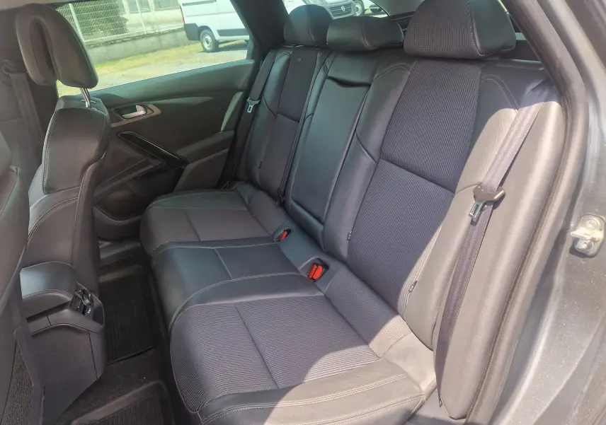 Vue intérieure côté droit des sièges arrière en cuir noir du Peugeot 508 SW gris shark, soulignant l'espace et la finition soignée.