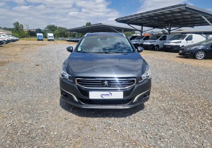 Vue frontale d'une Peugeot 508 SW gris shark 2015, avec calandre chromée et phares LED visibles.