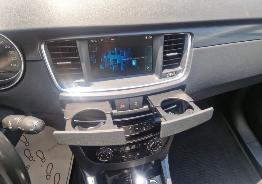 Vue intérieure du tableau de bord de la Peugeot 508 SW gris Shark, avec écran tactile et porte-gobelets déployés.