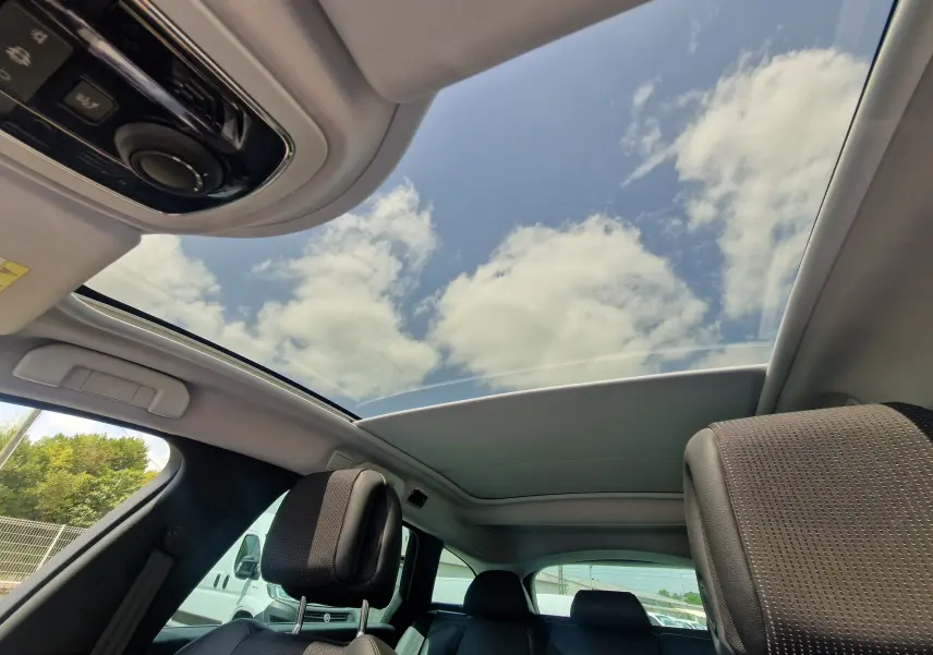 Vue intérieure du toit ouvrant panoramique du Peugeot 508 SW gris Shark, mettant en valeur les sièges avant et arrière en cuir.