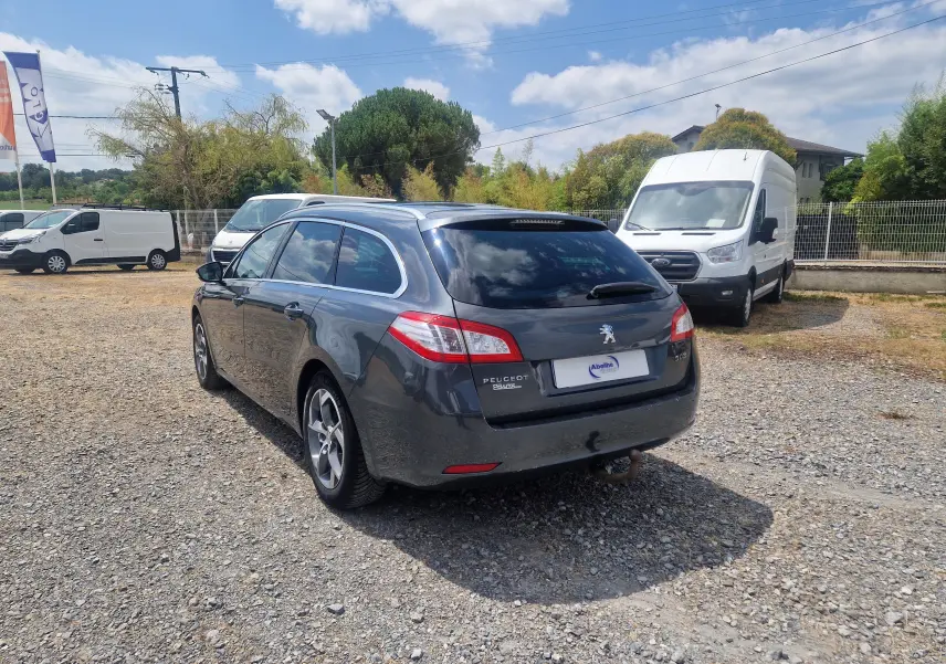 Peugeot 508 SW gris Shark vue 3/4 arrière droit sur parking, avec attelage et jantes alliage 17 pouces.