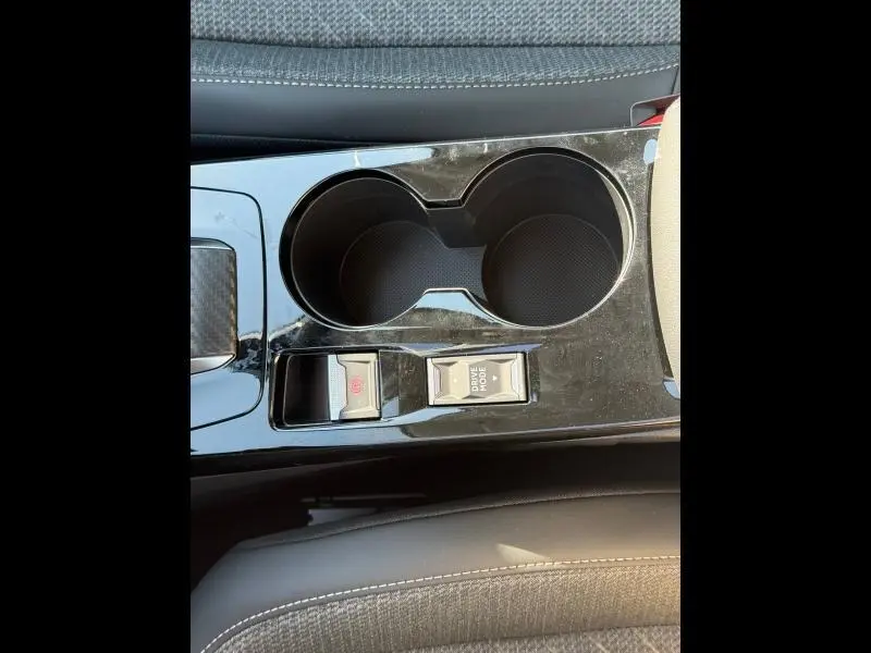 Gros plan sur la console centrale noire brillante avec porte-gobelets et commandes Drive Mode et frein à main électrique dans une Peugeot 208 gris Selenium.