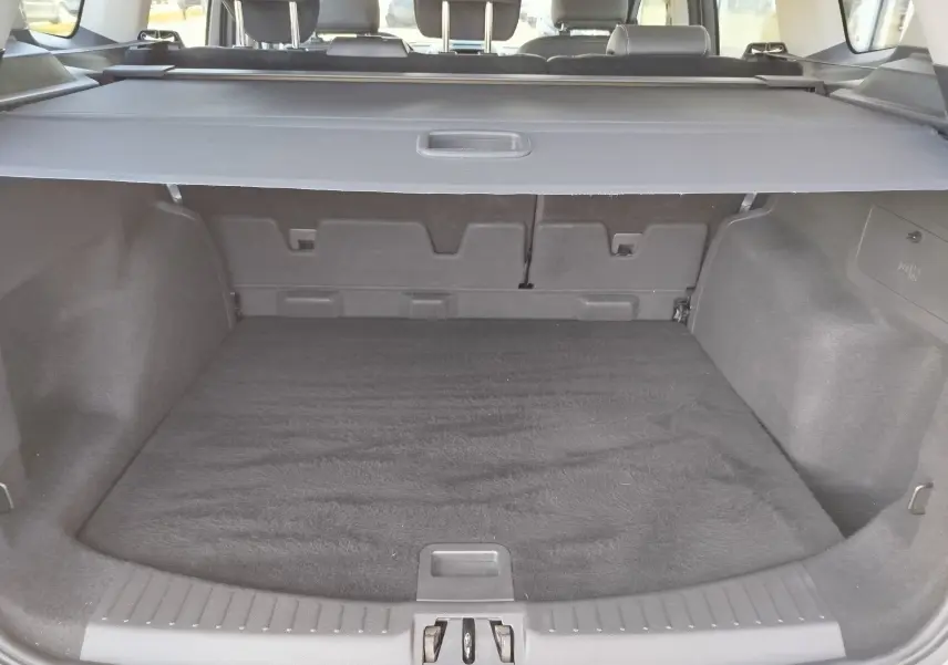 Coffre ouvert vu de l'arrière d'un Ford Kuga gris clair 2019, avec cache-bagages et intérieur noir.