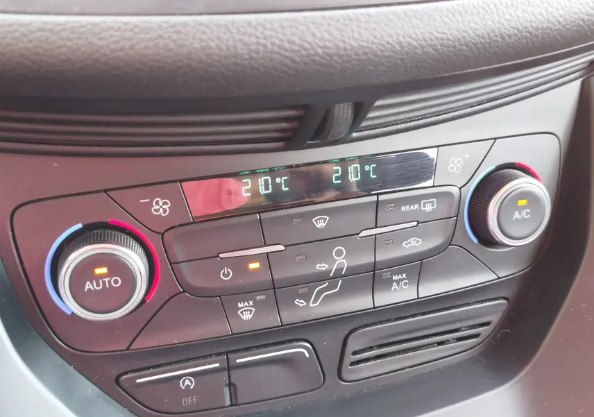 Panneau de climatisation du Ford Kuga 2019 gris clair, affichant 21°C avec réglages automatiques et boutons lumineux.