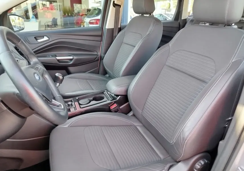 Vue intérieure avant droite du Ford Kuga 2019 avec sièges gris tissu et volant cuir visible au premier plan