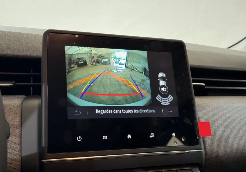 Écran tactile central de la Renault Clio gris clair montrant la caméra de recul avec lignes de guidage colorées.