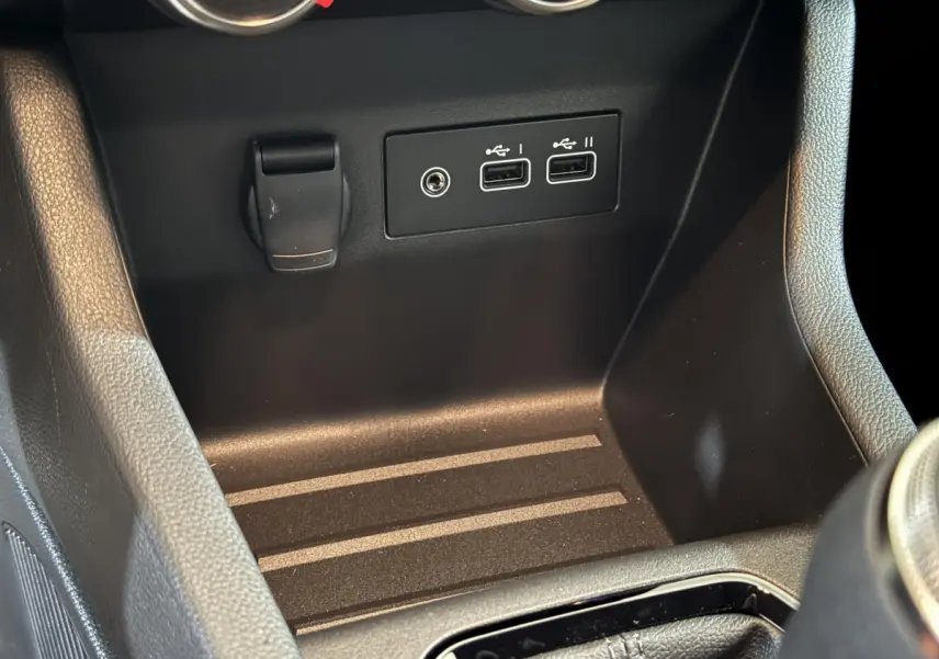 Gros plan sur la console centrale de la Renault Clio gris clair 2025 montrant ports USB et prise 12V.
