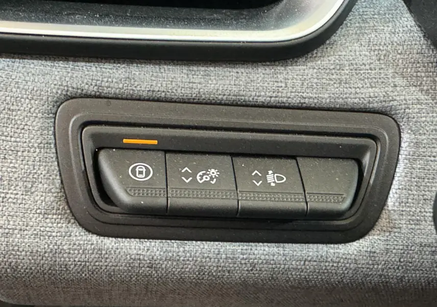 Gros plan sur les commandes d'éclairage et verrouillage intégrées dans la console tissu de la Renault Clio gris clair 2025.