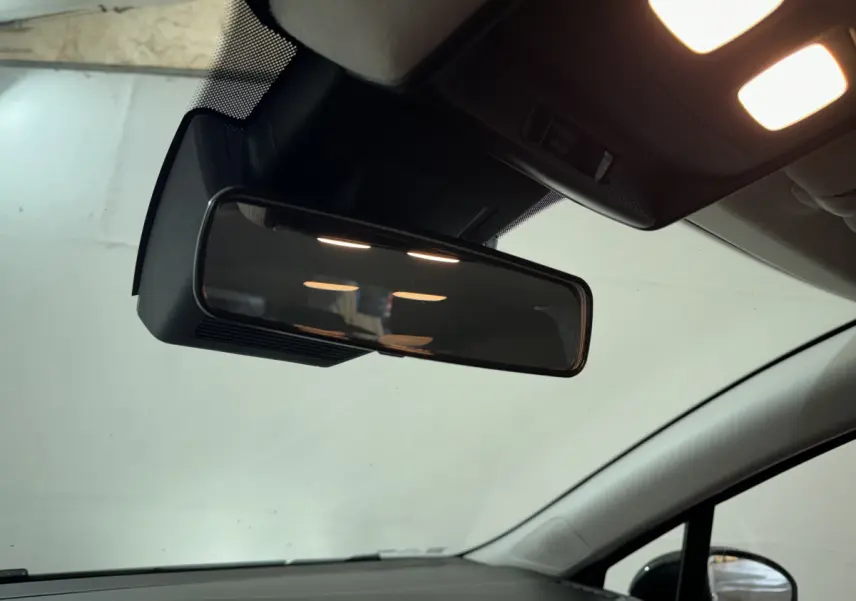 Vue intérieure rapprochée du rétroviseur central et du plafonnier éclairé de la Renault Clio gris clair 2025.