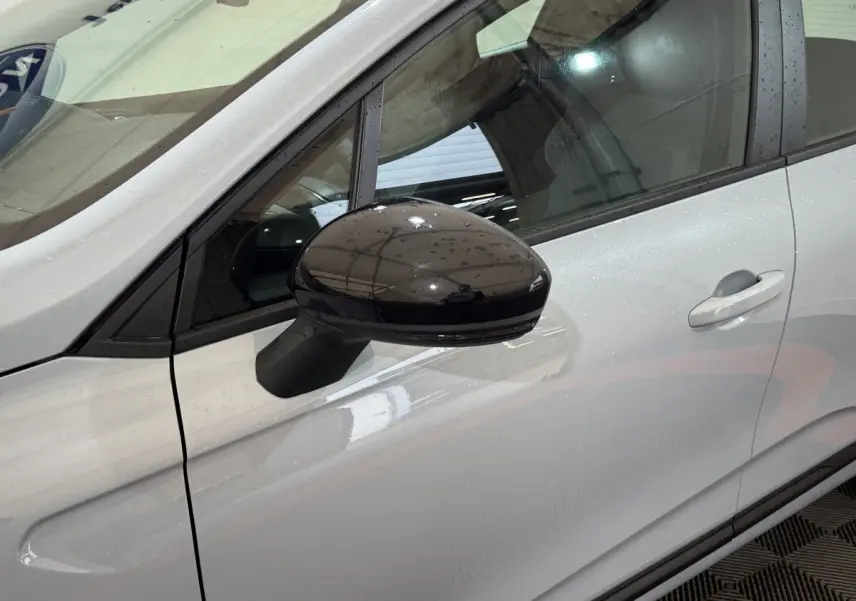 Rétroviseur noir en gros plan côté gauche sur la portière gris clair d'une Renault Clio Evolution 2025.