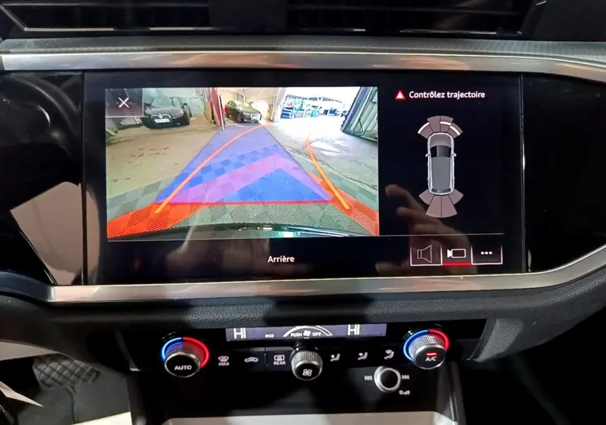 Écran tactile central de l'Audi Q3 noir 2020 montrant la caméra de recul et l'aide au stationnement arrière.
