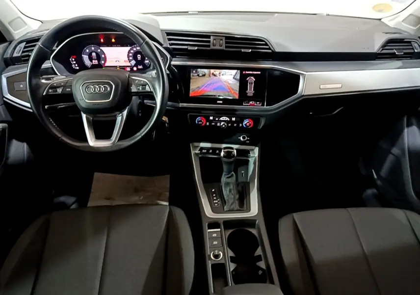 Intérieur noir d'Audi Q3 35 TDI 2020 vu de face, tableau de bord digital et écran tactile central allumé.
