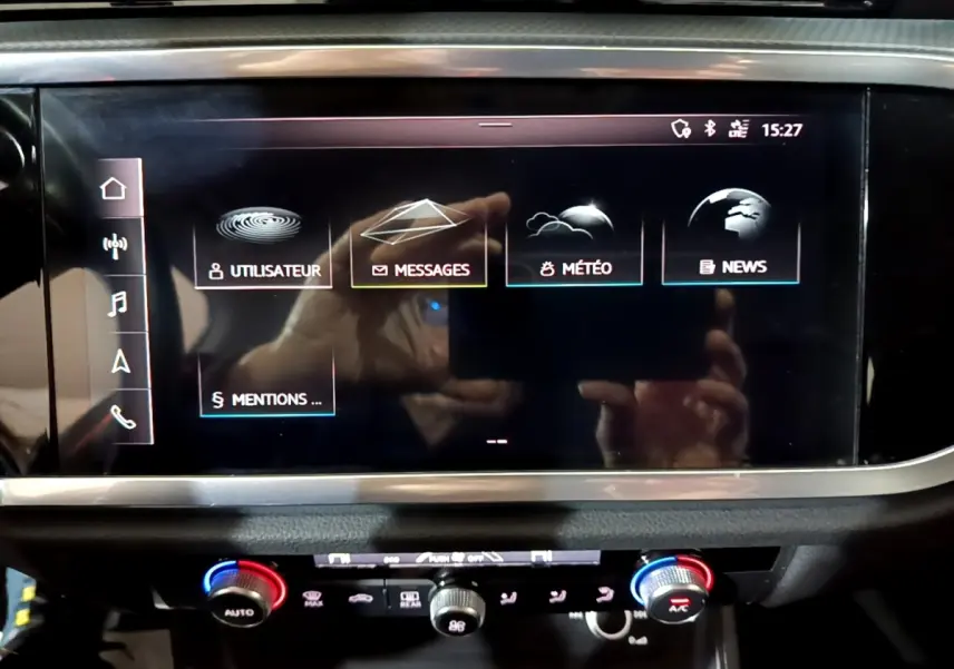 Écran tactile central et commandes de climatisation du tableau de bord de l'Audi Q3 noir, vue rapprochée intérieure.