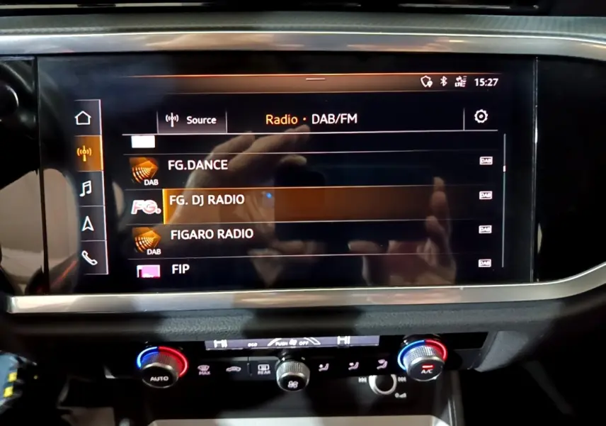 Écran tactile central affichant les radios DAB/FM dans l’Audi Q3 35 TDI Business Line noire, vue intérieure frontale.