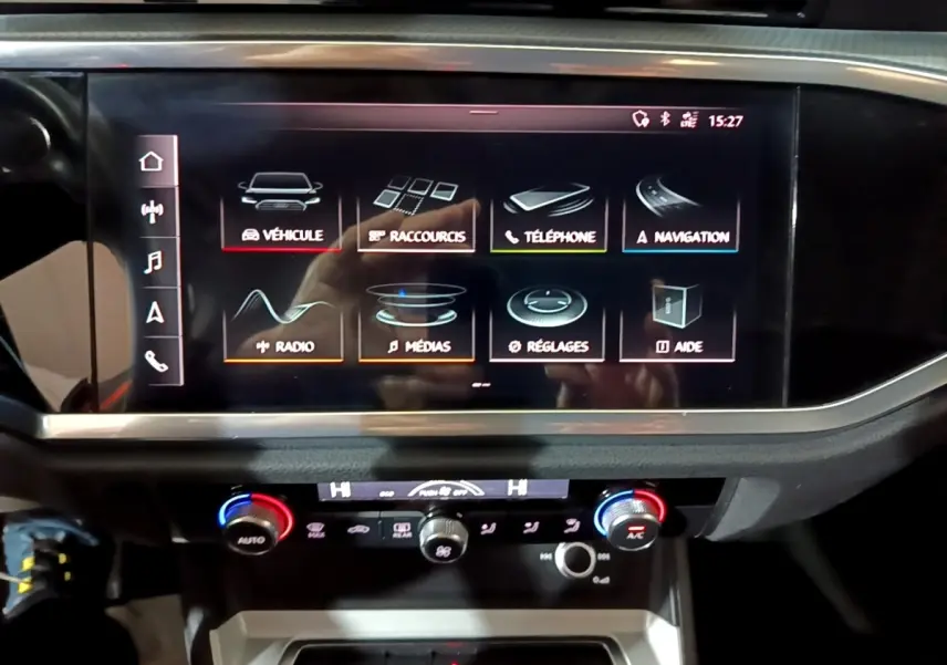 Écran tactile central et commandes climatisation du tableau de bord de l'Audi Q3 noir vue de face.