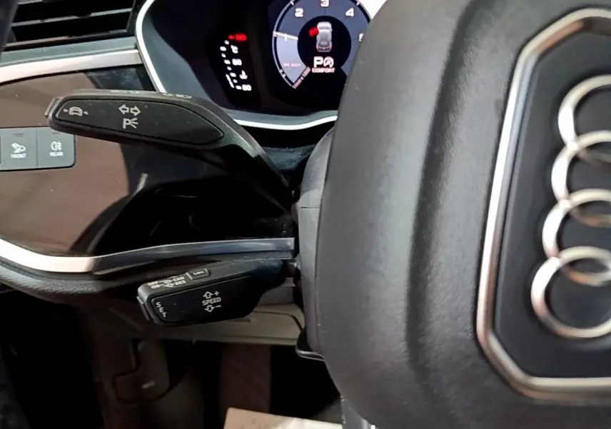 Gros plan sur le volant cuir noir d'Audi Q3 35 TDI 2020 avec commandes au volant et tableau de bord numérique.